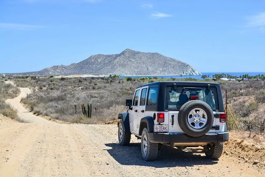 Jeep blanco en un camino de terracería hacia la costa