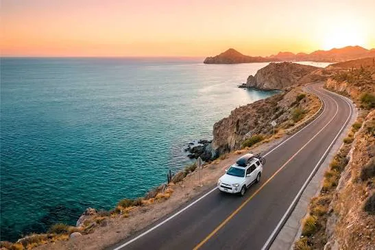 SUV blanco en una carretera costera al atardecer